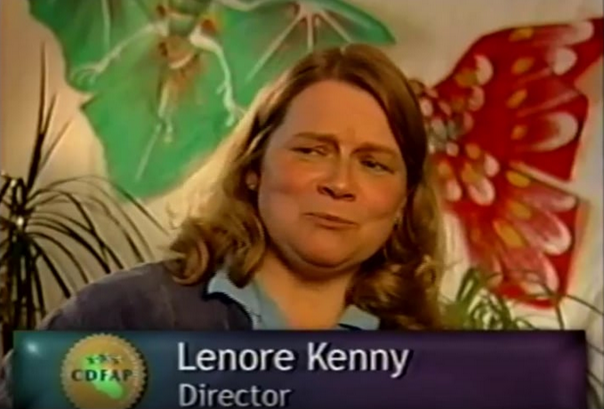 Woman looking away from camera; in the background there are butterfly-like drawings on a wall.