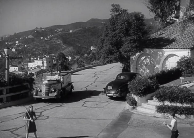 Two children playing baseball in a driveway while man in vehicle watches