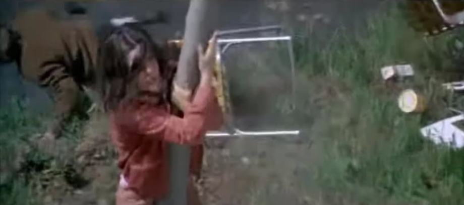 Woman holding on to a post outside as ground shakes; man falling behind her