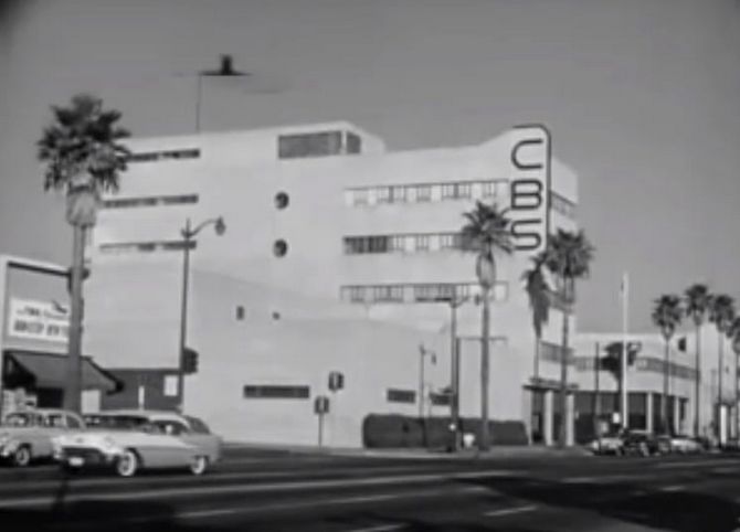 Photo of the outside of a building with logo CBS; building is next to a street with cars
