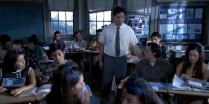 Teacher standing amid students in a classroom.